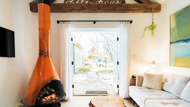 A cozy living room with a fireplace, a white sofa, and a wooden table.