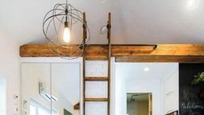 A modern kitchen with white cabinetry, a stainless steel refrigerator, and a wooden ladder.