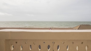 Une vue sur la plage depuis un balcon dont la rambarde est ornée d’ouvertures ovales.