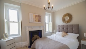 Une chambre à coucher avec un lit, une commode, une cheminée et un lustre.