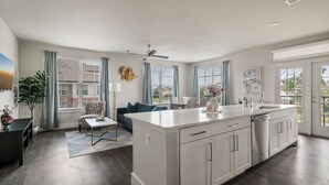 Una cocina moderna con una isla central, ventanas amplias y un rincón de comedor con sofá y mesa.