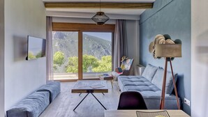 A modern living room with a sofa, a coffee table, and a lamp. There is a large window with a view of mountains. - KOMODY (Delphi)