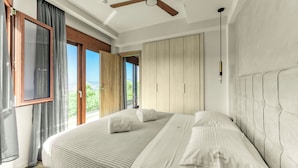 A bedroom with a large bed, a ceiling fan, and a view of the outdoors. - KOMODY (Delphi)