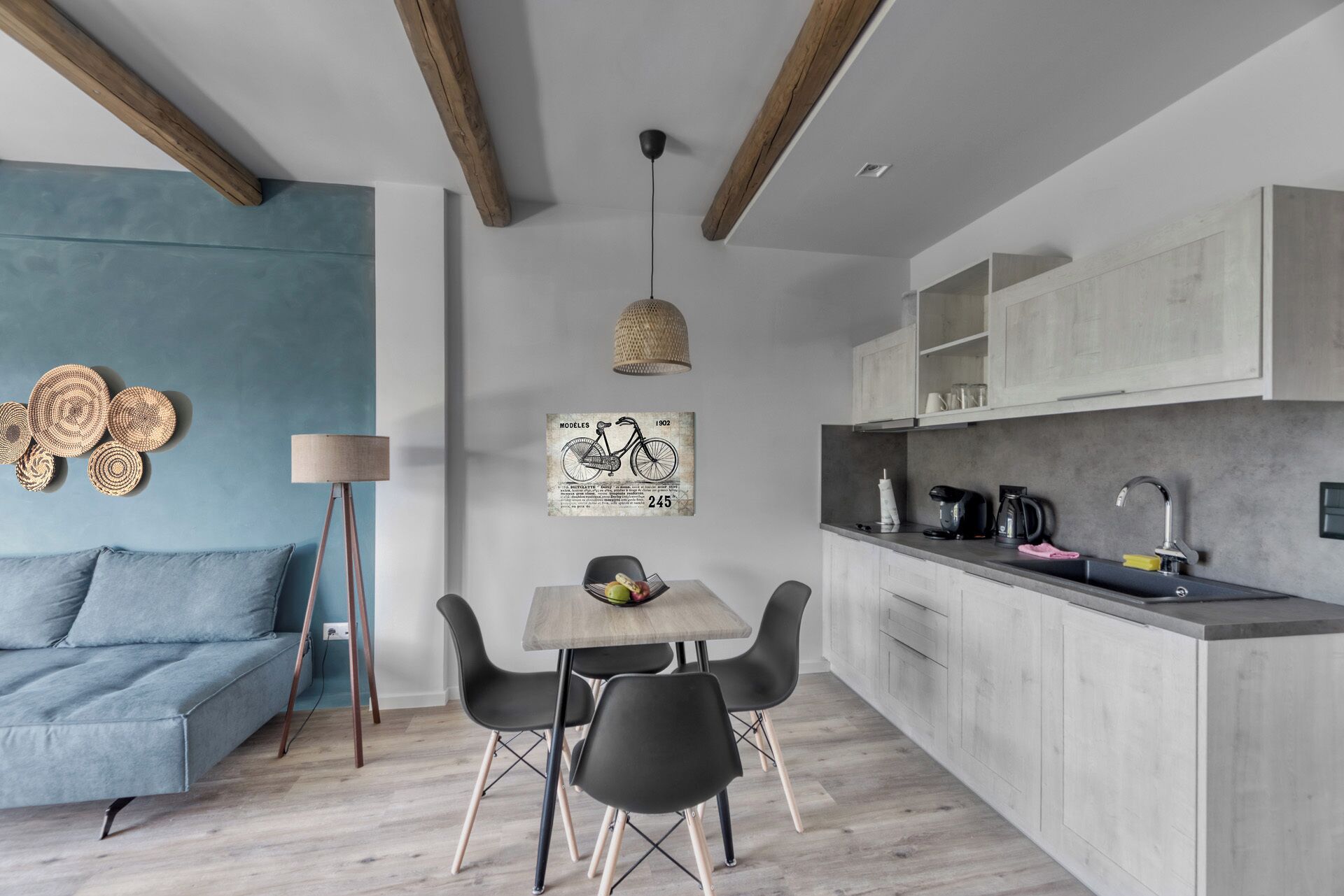 A modern kitchen with a dining area, featuring a wooden ceiling, a light fixture, and a vintage bicycle poster.