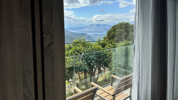 A balcony with a glass railing overlooking a mountainous landscape. - KOMODY (Delphi)