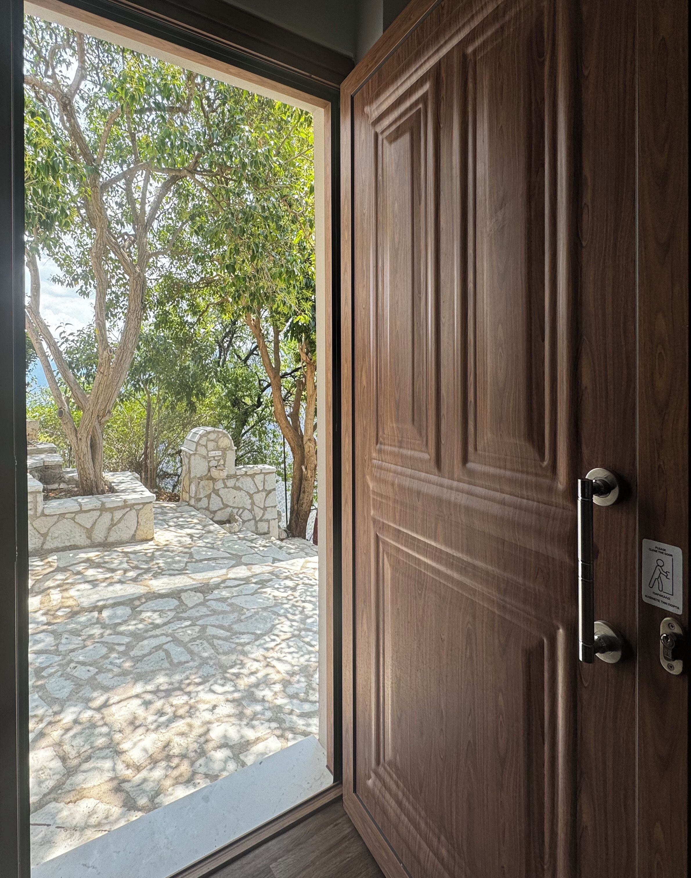 Μια ξύλινη πόρτα με μεταλλική λαβή και μια πινακίδα που υποδεικνύει το σημείο πρόσβασης με χρήση μαγνητικής κάρτας.