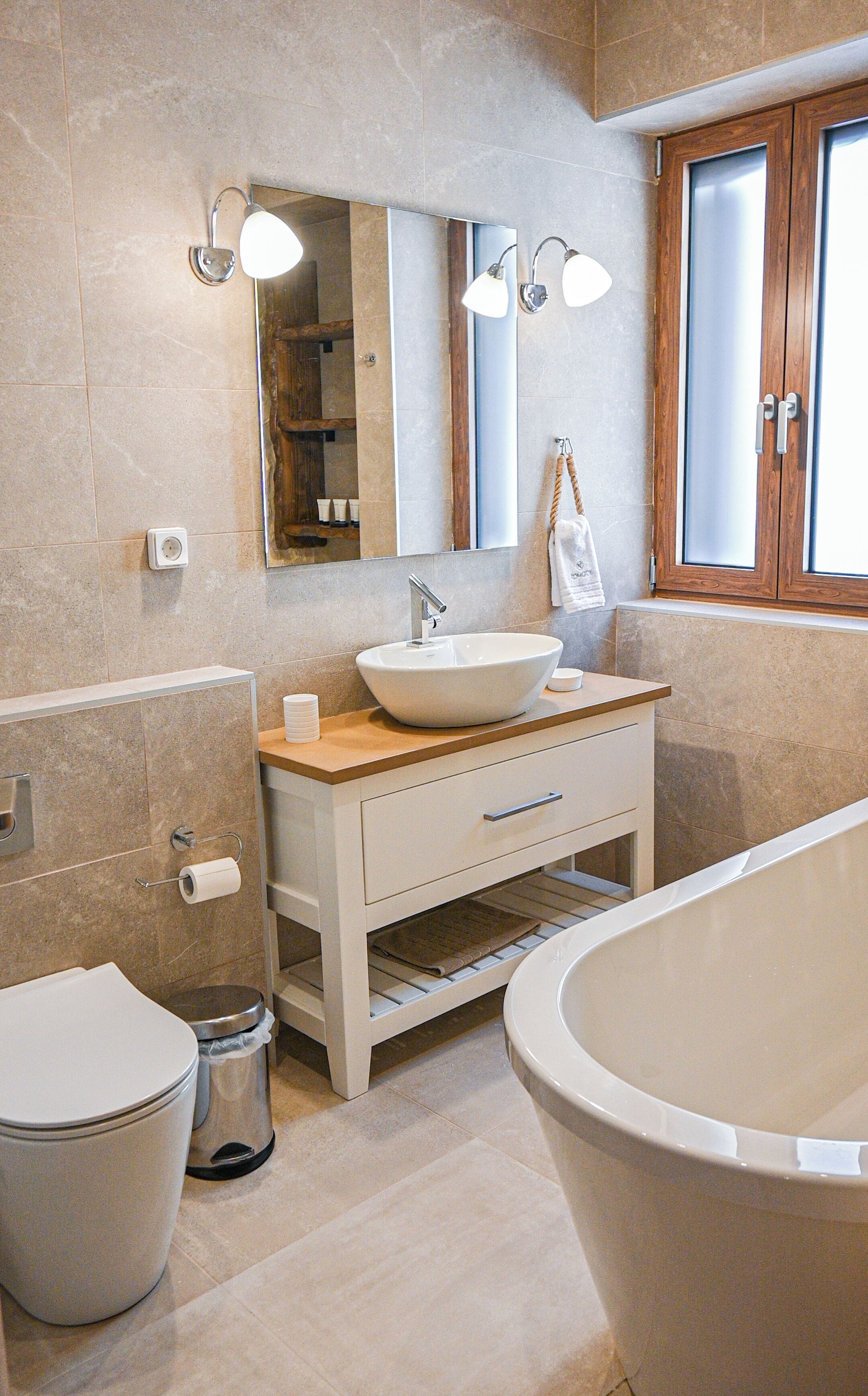 Un baño moderno con una bañera independiente, un espejo grande y un mueble lavamanos.
