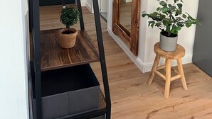 A staircase with wooden steps and metal railings, leading to a room with a large mirror and a small stool with a potted plant. - Park View Apartment (Bremerhaven)