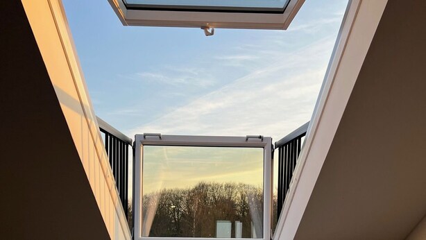A room with a skylight, a sofa, and a view of trees. - Park View Apartment (Bremerhaven)