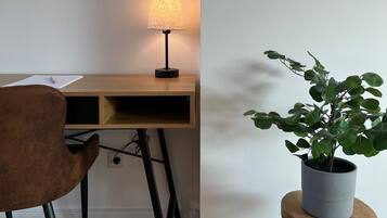 Ein Arbeitsplatz mit Schreibtisch, Stuhl, Lampe und Topfpflanze.