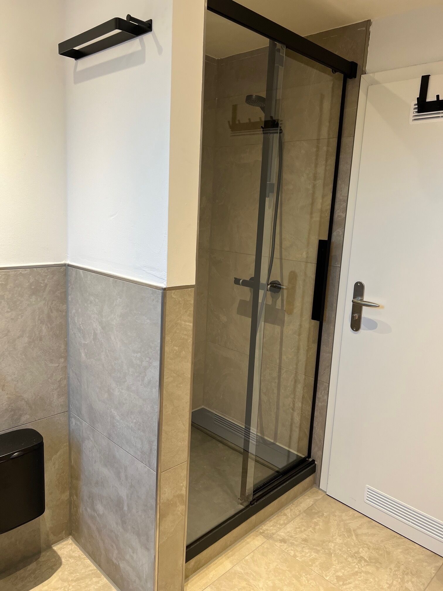A modern bathroom with a glass shower enclosure, a towel rack, and a toilet.