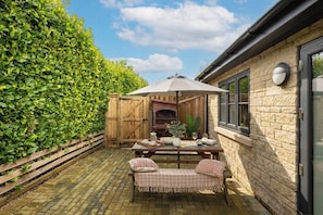 A patio with a table, chairs, and a pizza oven.