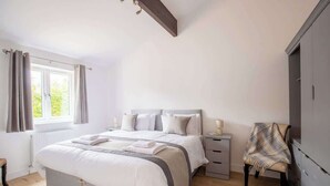 A bedroom with a bed, bedside tables, a chair, and a window with curtains.