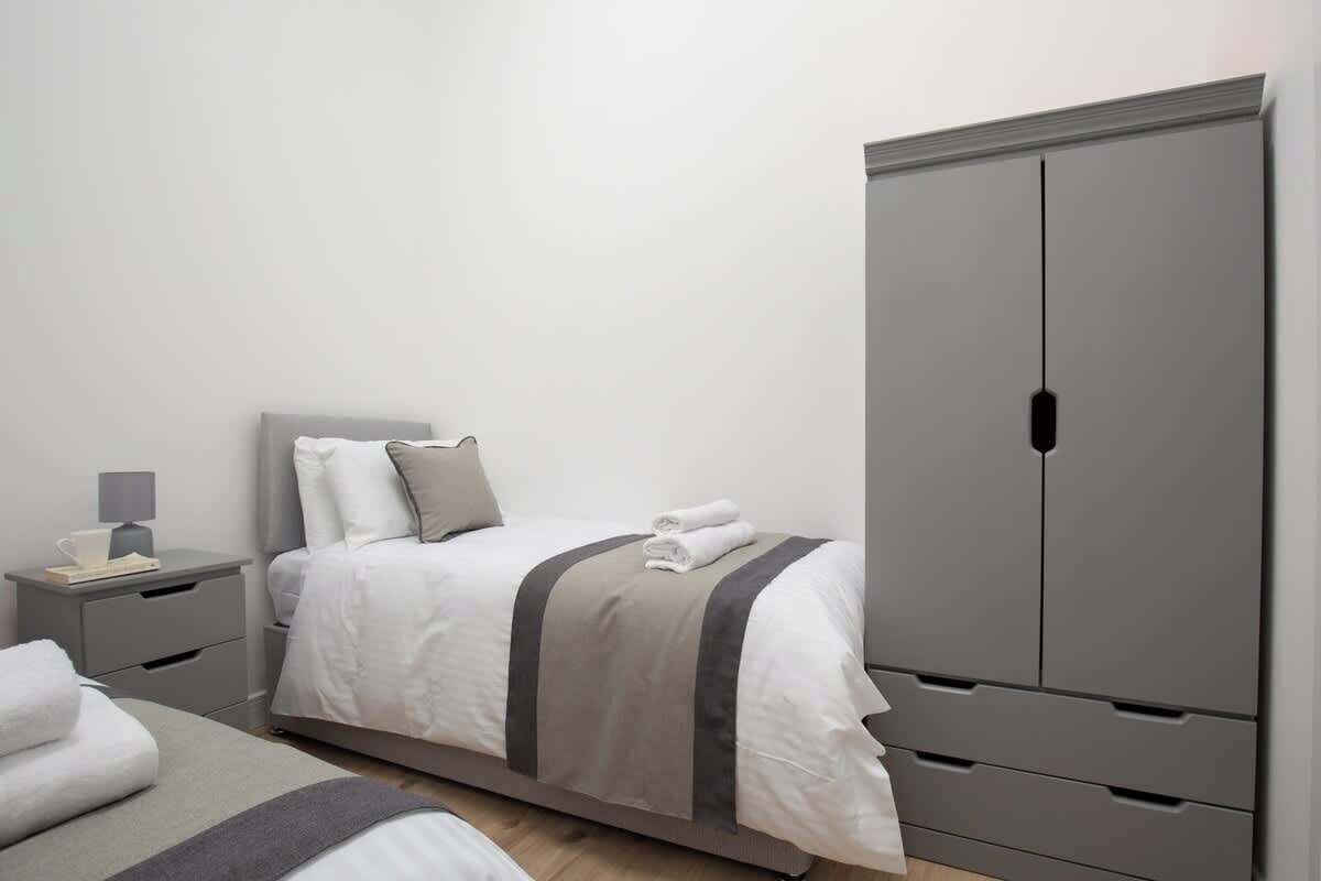 A bedroom with a bed, nightstand, and wardrobe.