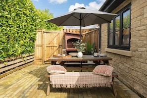 A patio with a wooden table, a bench, and an umbrella.