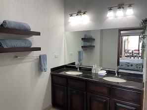 A bathroom with two sinks, dark wood cabinets, a large mirror, and towel racks with folded towels.