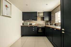 A modern kitchen with dark cabinets, a microwave, a stove, and a sink.