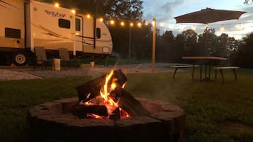 A campsite with a fire pit, string lights, and a flyte RV.