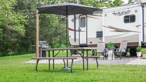 Ein Flyte Wohnmobil mit Picknicktisch und Grill, umgeben von viel Grün.