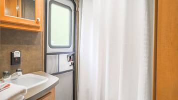 A bathroom with a sink, mirror, and window.