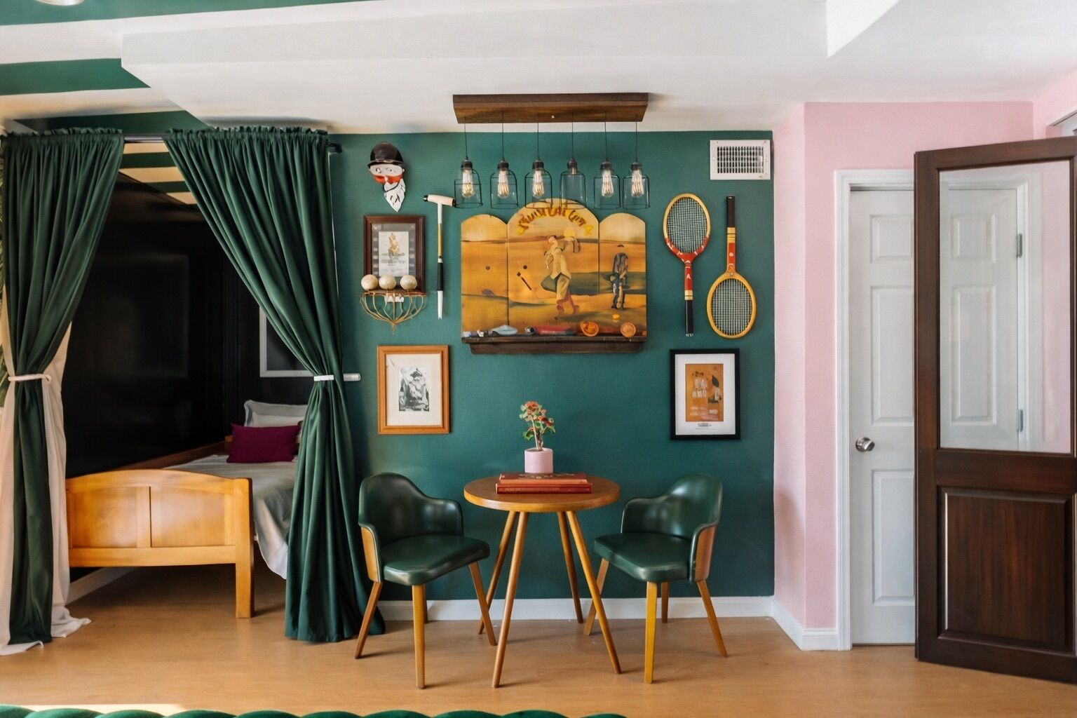 A room with a bed, two chairs, a table, a painting, and a door.