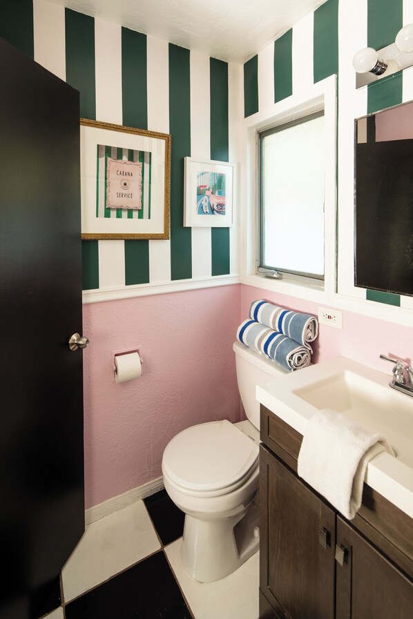 A bathroom with a toilet, sink, and framed pictures on the wall.