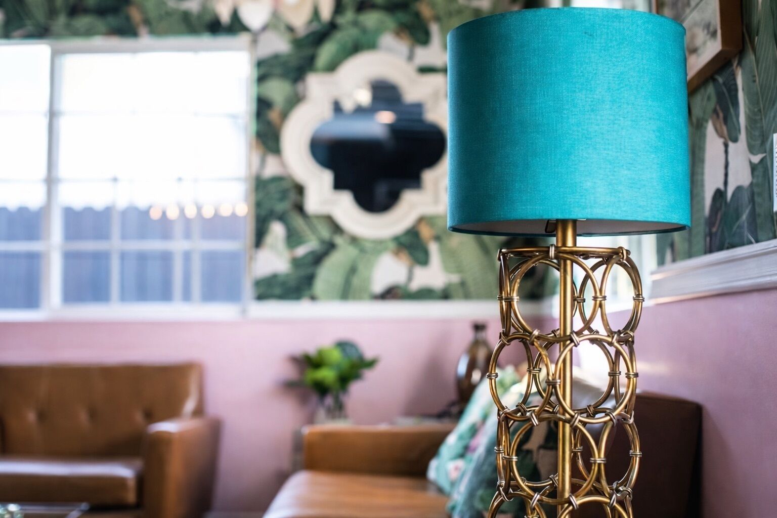 Quarto com papel de parede estampado, um sofá e uma luminária com cúpula azul.