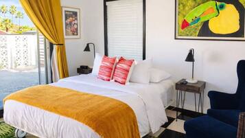 Una habitación de hotel con una cama, una mesita de noche, una silla, una ventana con cortinas y un cuadro en la pared.
