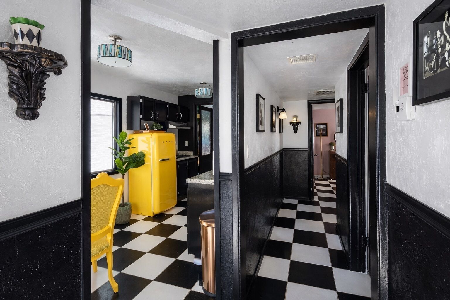 A hallway with a checkered floor, a yellow refrigerator, and a black and white decor theme.