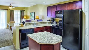 Eine kleine Küche mit Granit Arbeitsplatten, einem schwarzen Kühlschrank und Holzschränken.