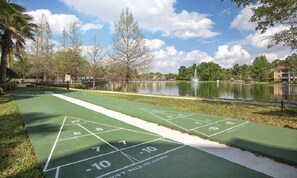 Un terrain de jeu de shuffleboard avec un étang et des arbres en arrière-plan.