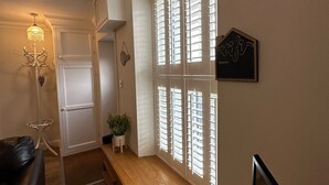 A hallway with a wooden bench, a door, a potted plant, and a wall-mounted sign. - The Cosy Cottage Retreat! Long Stay Discounts (Llantrisant)