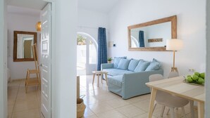 Un salon moderne avec un canapé bleu clair, une table à manger en bois et un grand miroir au mur.