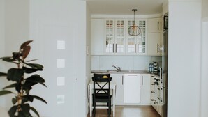 Une cuisine moderne avec des meubles blancs, une chaise noire et un luminaire suspendu.