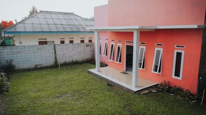 A residential building with a red exterior and a white porch. - homestay sembiring dua (Megamendung)