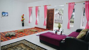 Una habitación con un sofá, un tapete estampado, una mesita y una puerta que da al exterior.