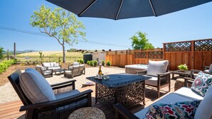 An outdoor patio area with a table and chairs, a small grill, and a wooden fence. - Luxe Healdsburg 3BR Home + Comp Ridge Wine Tasting (Healdsburg)