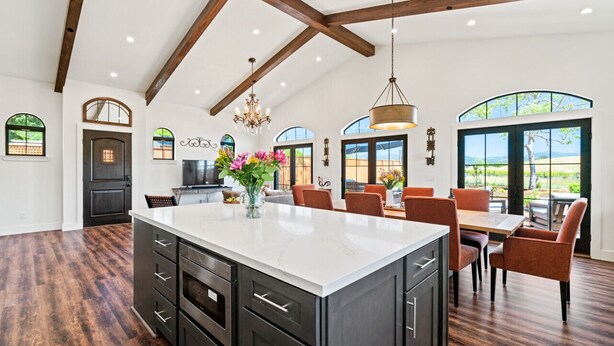 A spacious kitchen with a large island, dark cabinetry, and a view of the outdoors through large windows. - Luxe Healdsburg 3BR Home + Comp Ridge Wine Tasting (Healdsburg)