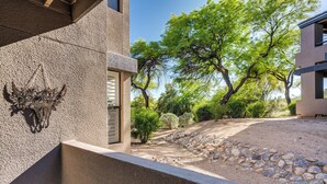 A modern building with a stone facade, a decorative bull head sculpture, and a landscaped area with trees and a gravel path.