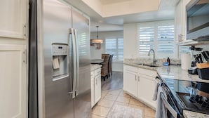 A modern kitchen with stainless steel appliances, a water dispenser, and a granite countertop.