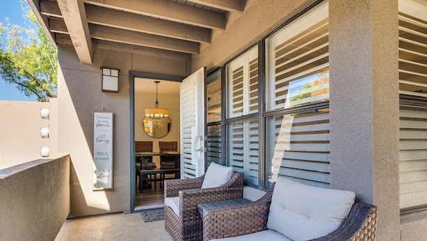 A covered outdoor seating area with wicker furniture and a sign with motivational phrases.