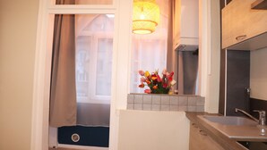 A kitchen with a window, a sink, and a vase of flowers.