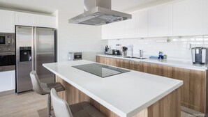 A modern kitchen with white cabinetry, stainless steel appliances, and a central island. - Relaxing Waterfront Getaway in Puerto Aventuras (Puerto Aventuras)
