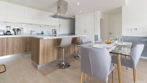 A modern kitchen with a central island, bar stools, and a dining table set for four. - Relaxing Waterfront Getaway in Puerto Aventuras (Puerto Aventuras)
