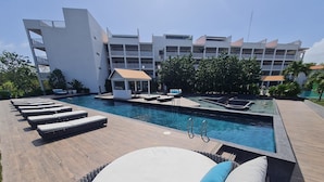 A pool area with lounge chairs and a building in the background. - Relaxing Waterfront Getaway in Puerto Aventuras (Puerto Aventuras)