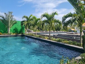 A swimming pool with clear blue water, surrounded by palm trees and a green wall. - Relaxing Waterfront Getaway in Puerto Aventuras (Puerto Aventuras)