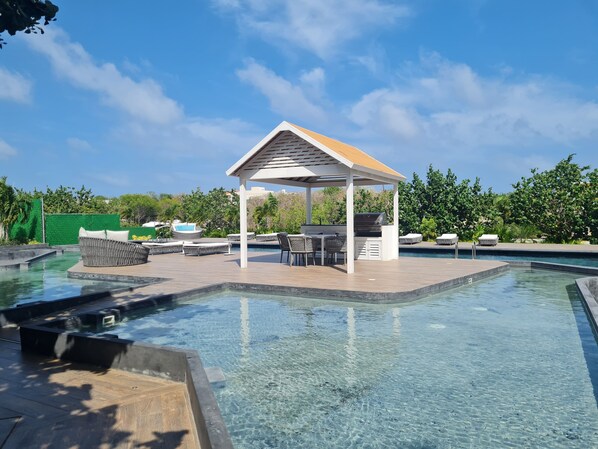 A pool area with a covered seating area, lounge chairs, and a hot tub. - Relaxing Waterfront Getaway in Puerto Aventuras (Puerto Aventuras)