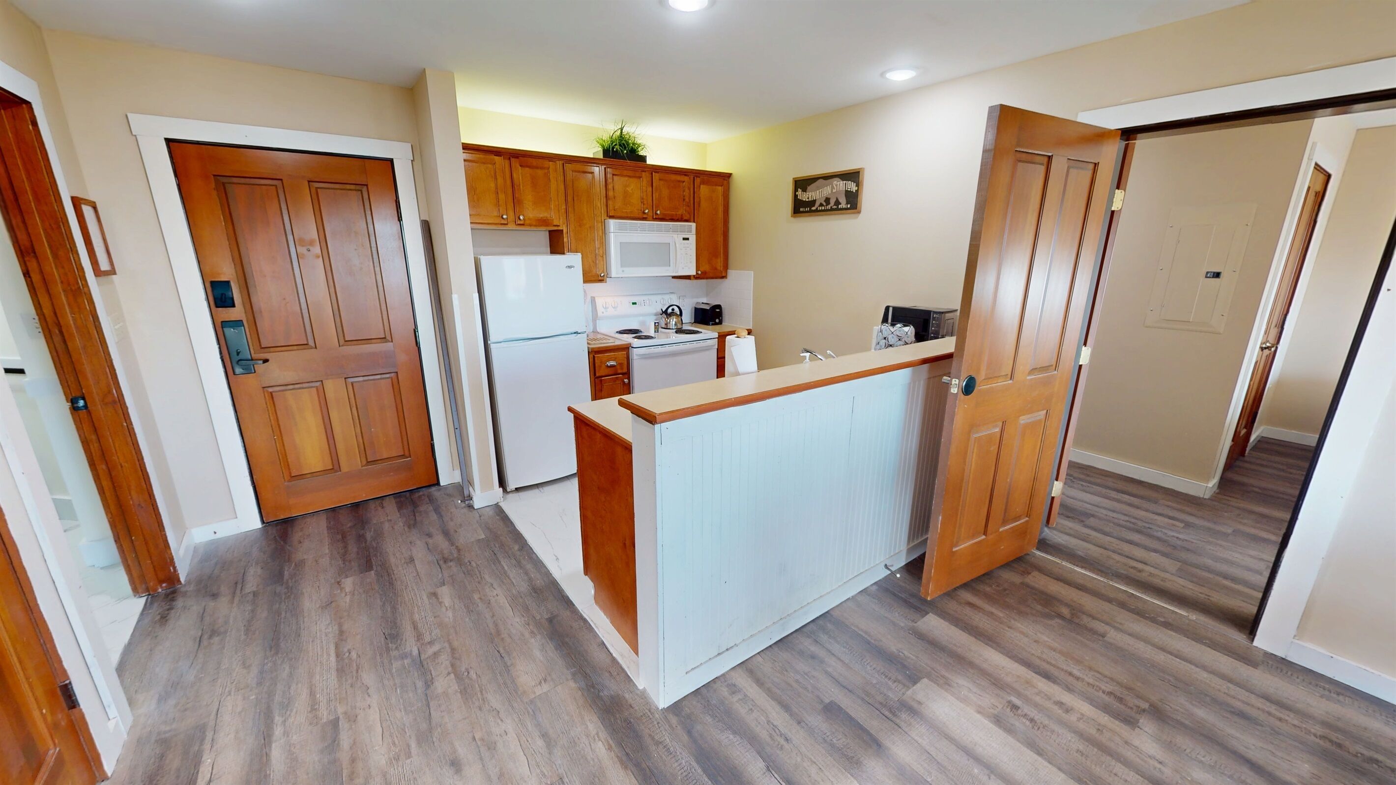 A compact kitchen with wooden cabinets, a microwave, a refrigerator, and a small island counter.