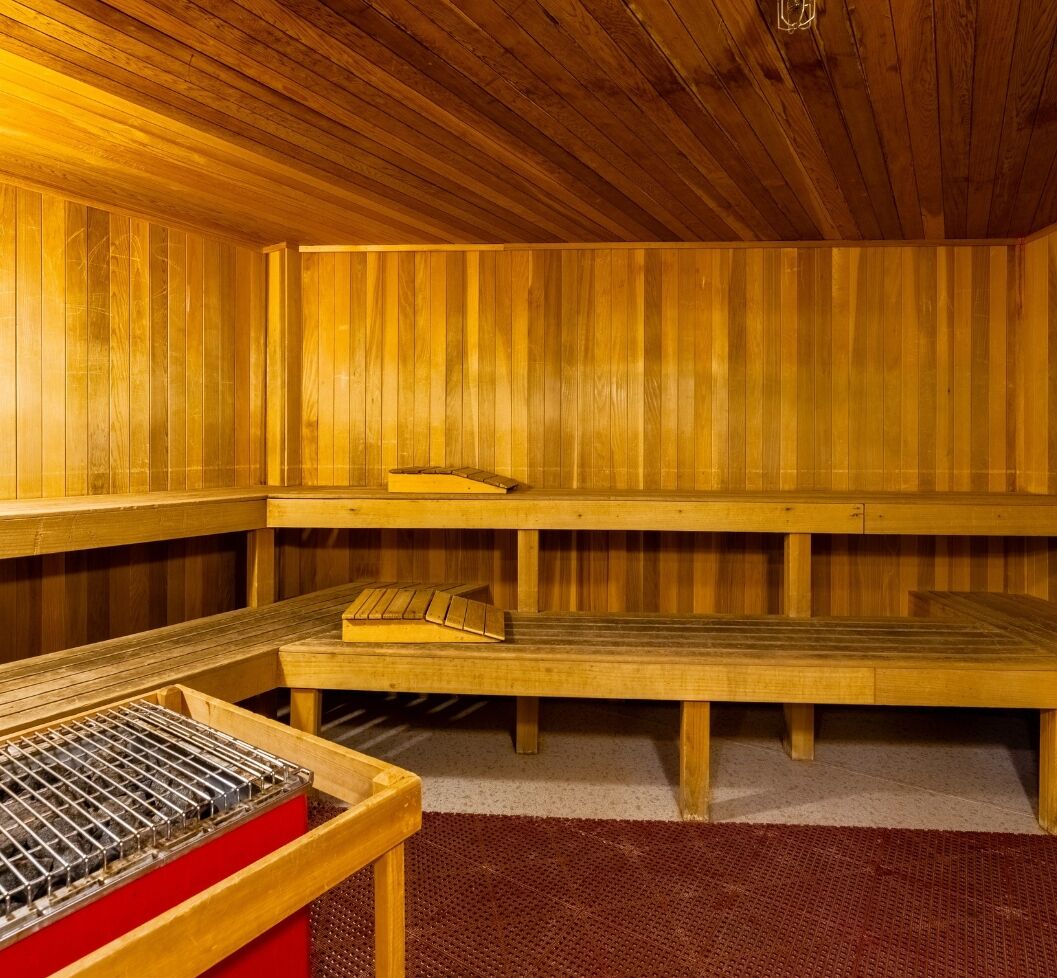 Uma sauna com bancos de madeira e uma grelha de metal.