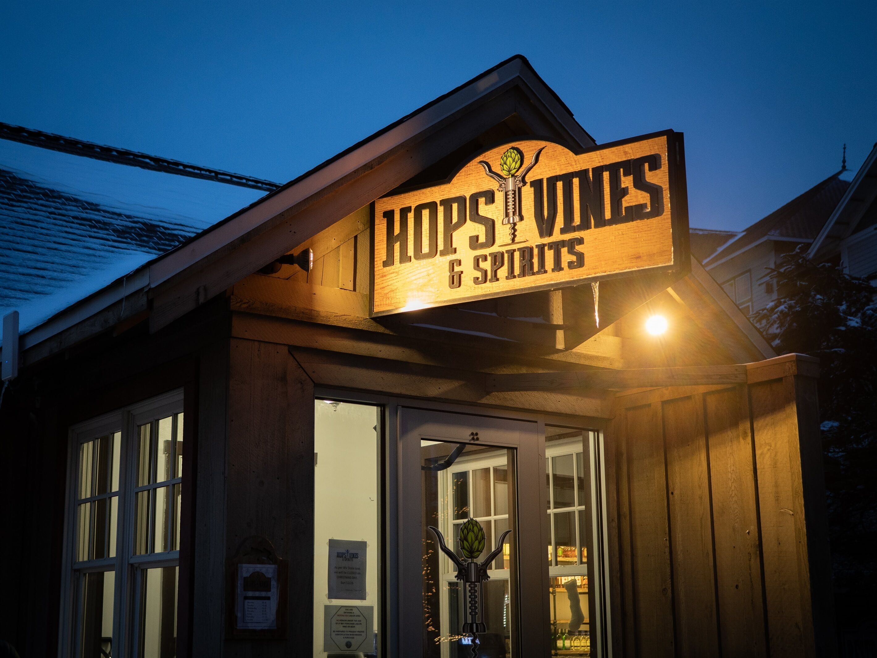A wooden storefront with a sign reading "HOPS VINES & SPIRITS".